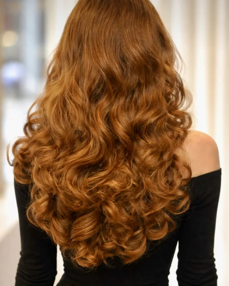 Long copper-red hair styled in voluminous curls